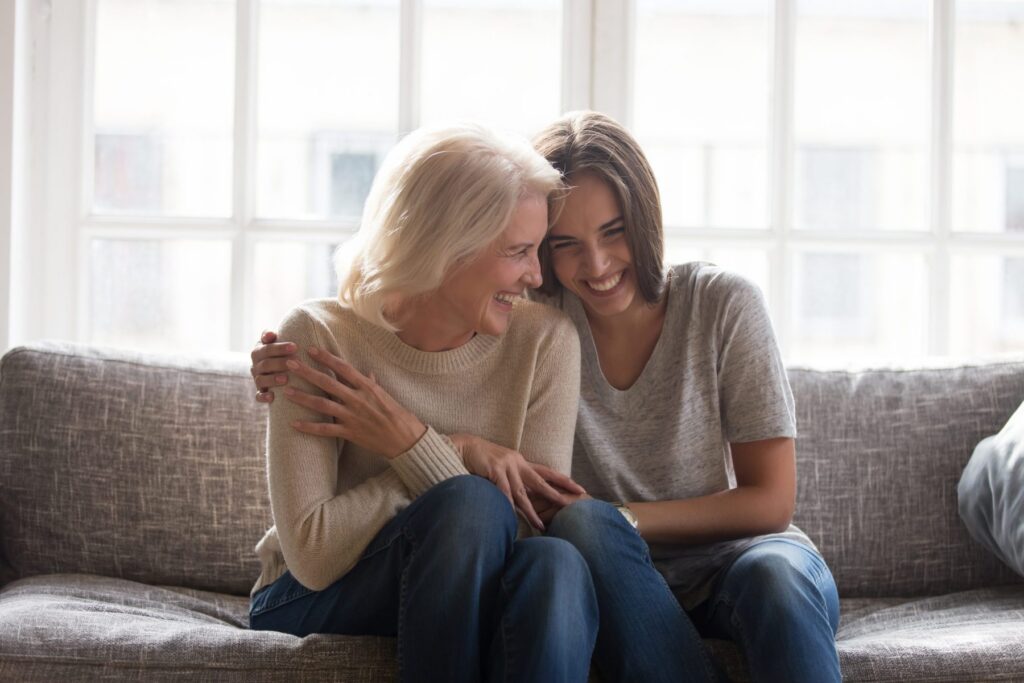 Two people sit closely on a couch, smiling and embracing, with a window in the background, looking over paperwork on LaGrange Estate Planning.