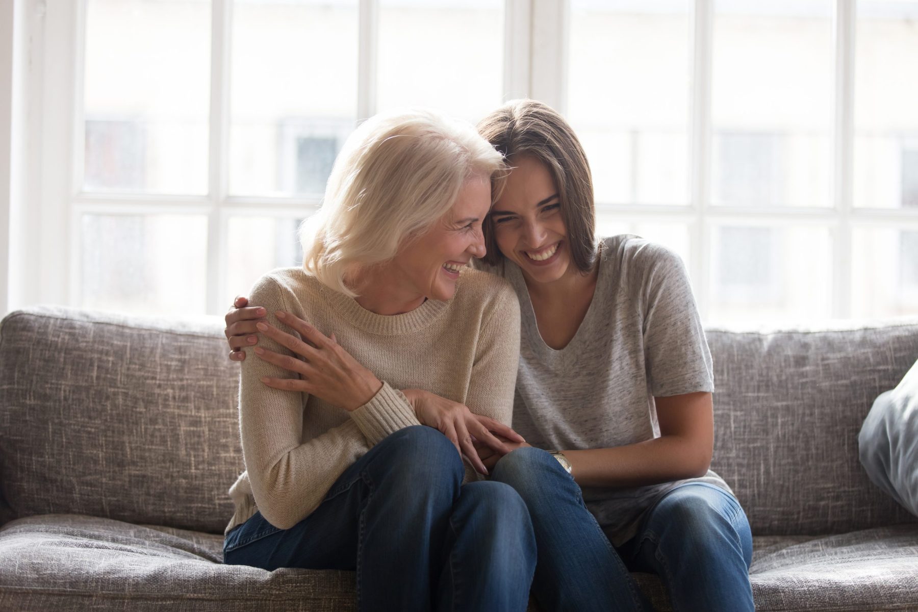 Two people sit closely on a couch, smiling and embracing, with a window in the background, looking over paperwork on LaGrange Estate Planning.