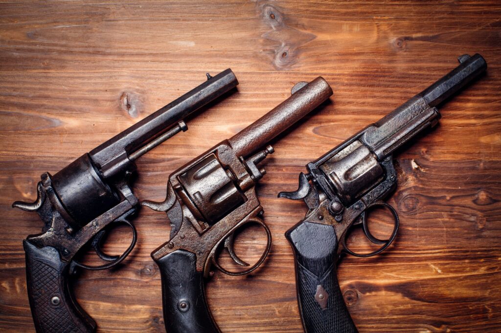Three vintage revolvers with black handles are displayed side by side on a wooden surface, reminiscent of items you might find in a will attorney Westmont office specializing in estate collections.