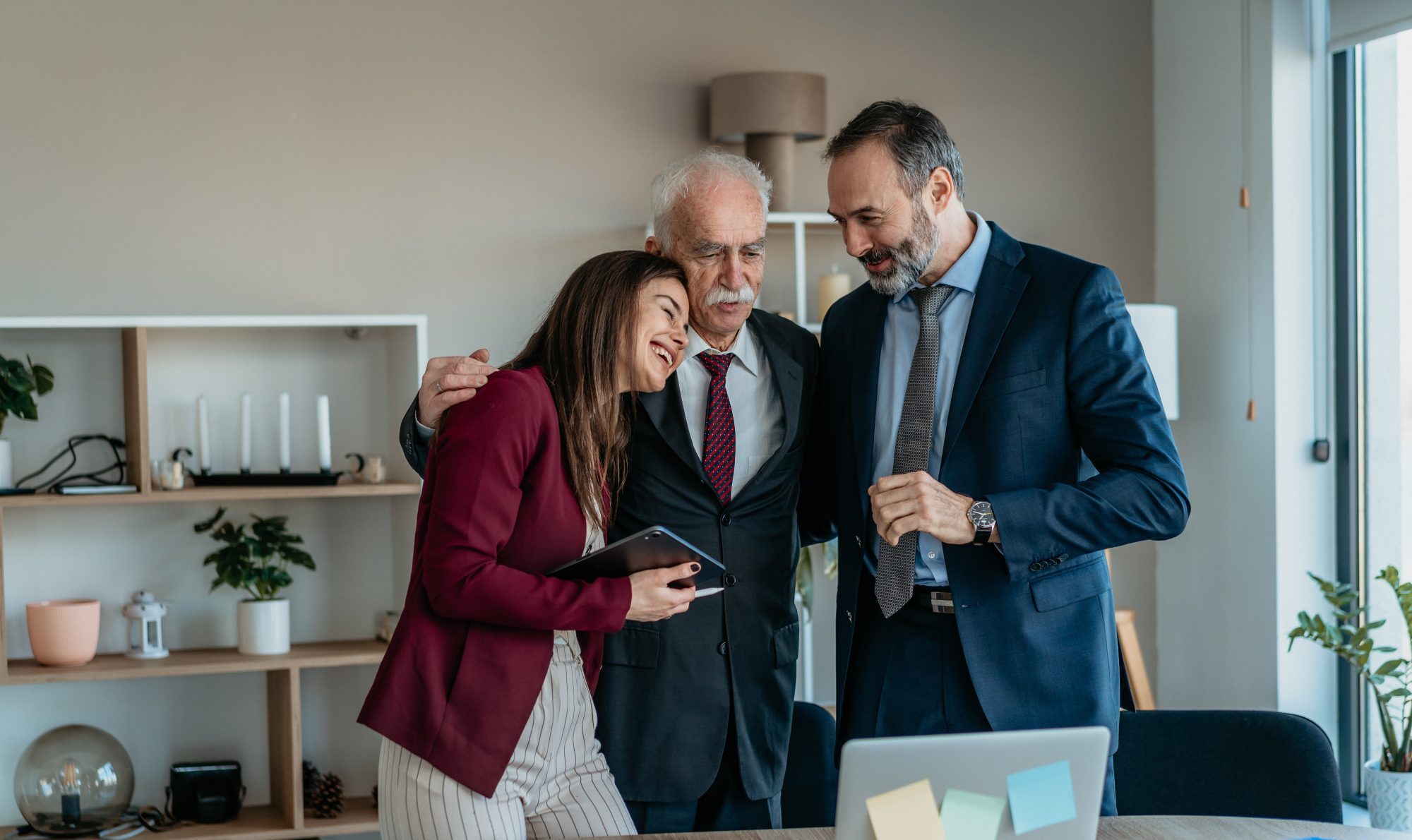 Three people in business attire stand together in an office, showing family business with succession to younger generation. Meet with estate planning lawyer Deerfield for assistance.