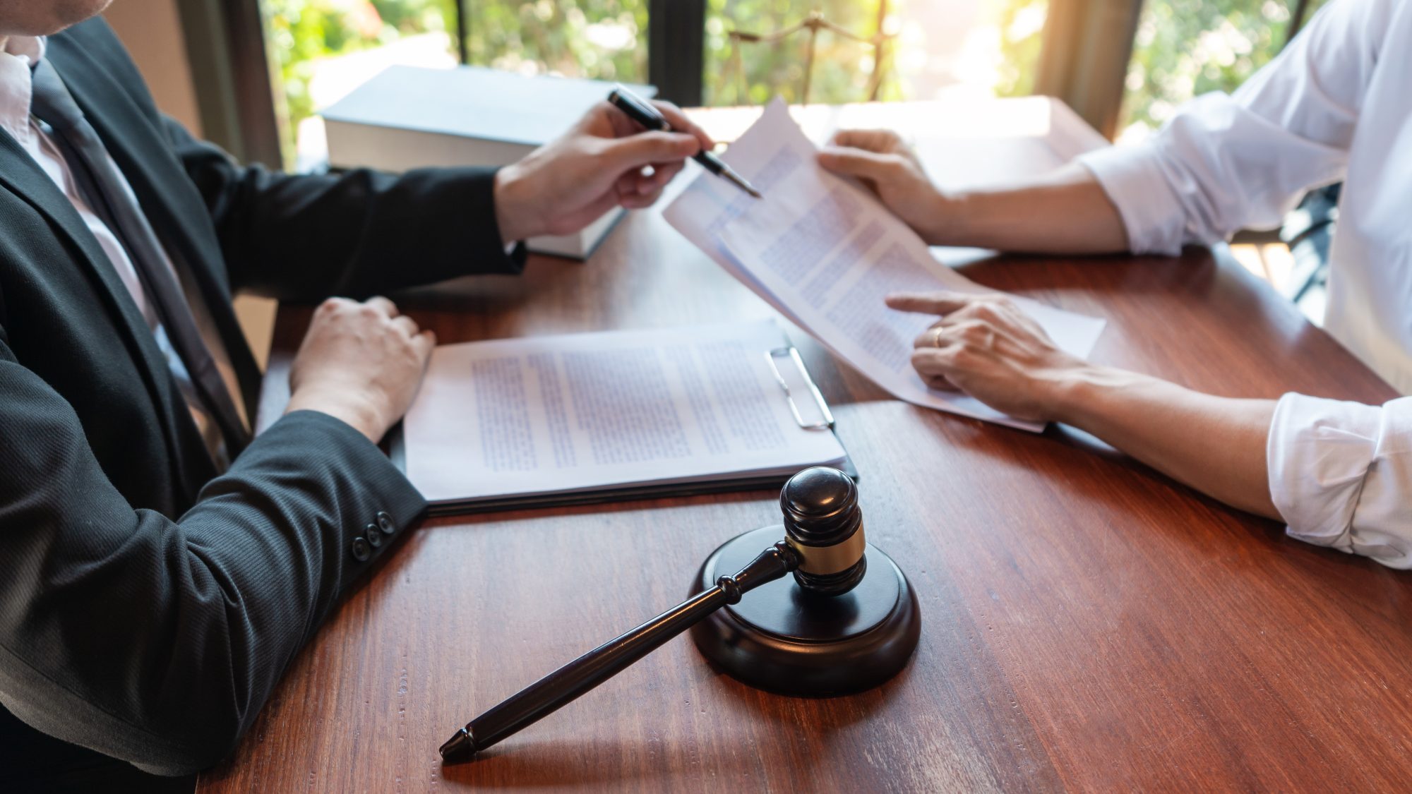 Two people reviewing documents at a wooden table with a gavel in the foreground, focused on securing their future through Brookfield Elder Law.