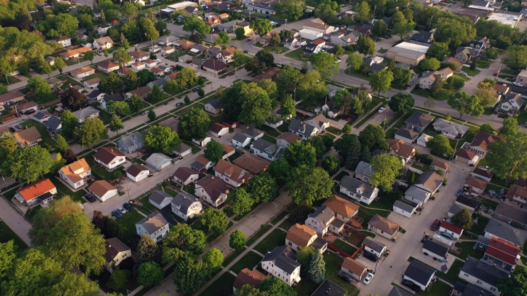 Aerial view of a suburban neighborhood with tree-lined streets, houses, and cross streets, capturing the charm of Hinsdale Wills community life.