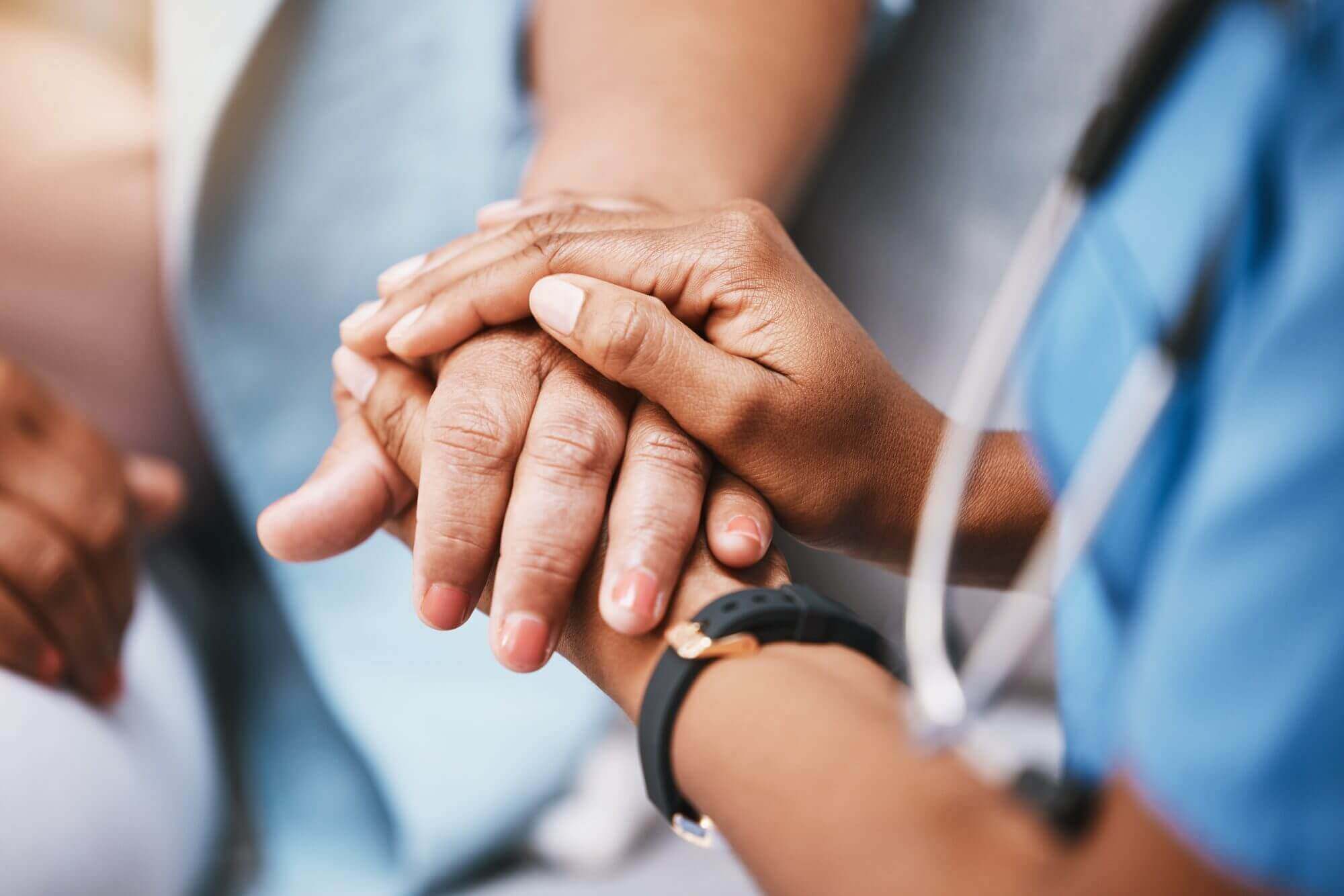 A medical professional in scrubs, much like the compassionate guidance found at Western Springs Estate Administration, holds the hands of a patient, offering comfort and support.