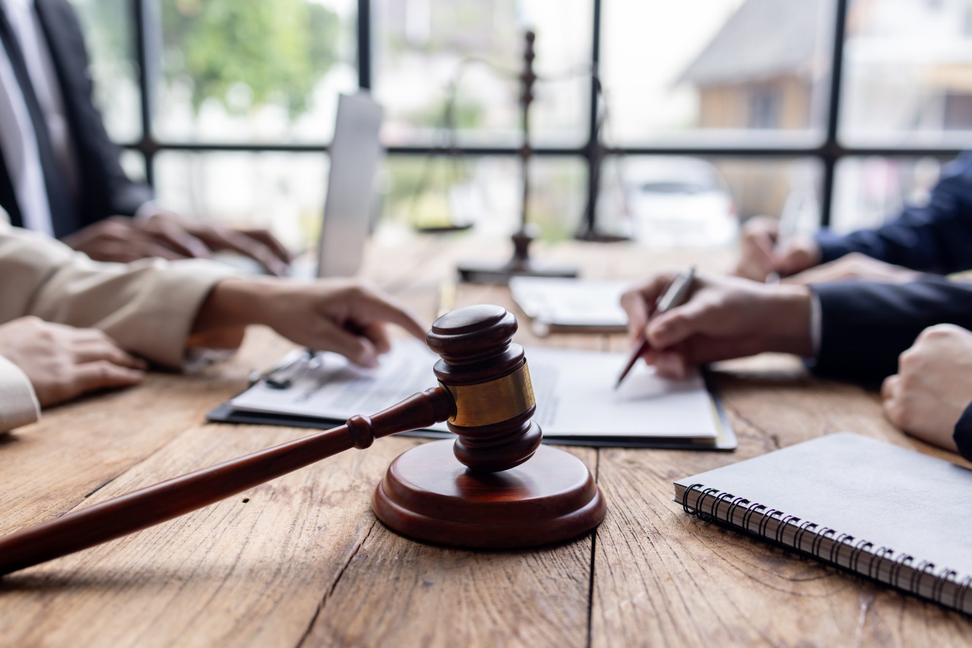 A wooden gavel on a table with people in reviewing documents, when establishing a trustee for trust work with LaGrange Trusts Lawyer.