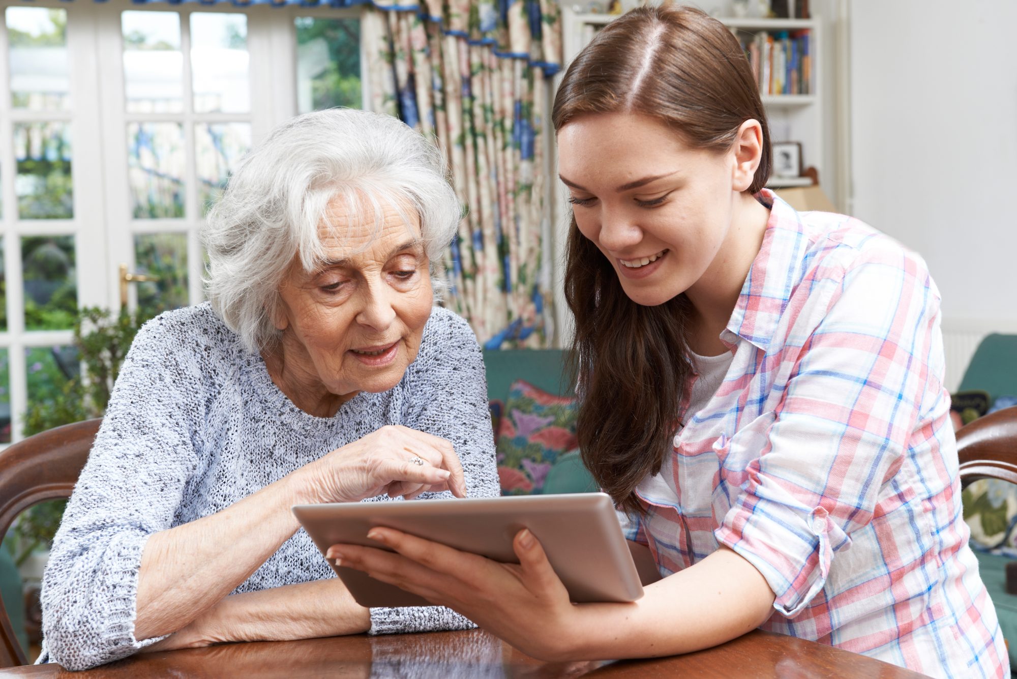 An elderly woman and a young woman sit at a table looking at a tablet together, when you need access to senior loved one's email account turn to Hinsdale Estate Planning Attorney for legal ways.