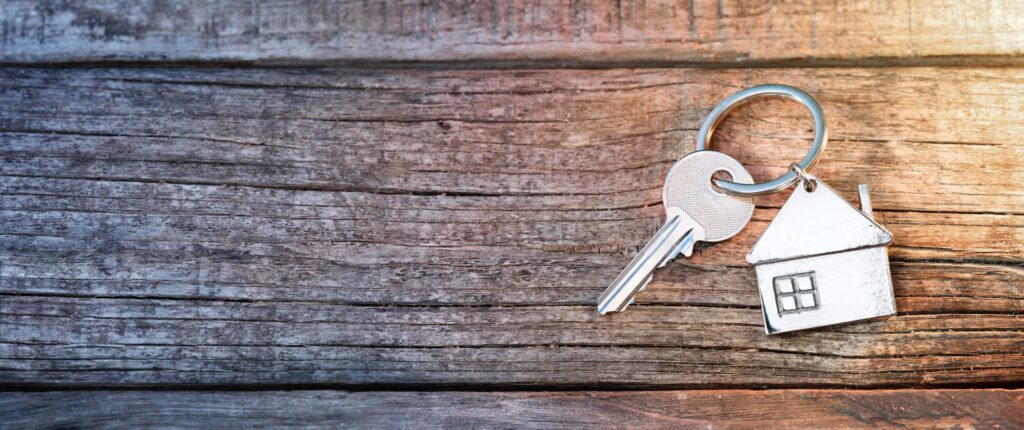 A house key with a keychain shaped like a house rests on a wooden surface, symbolizing the comfort and security offered by LaGrange Park Trusts.