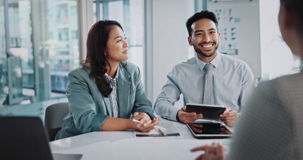 Two people in business attire sit at a table, engaging in conversation about LaGrange Estate Planning. One is holding a tablet.