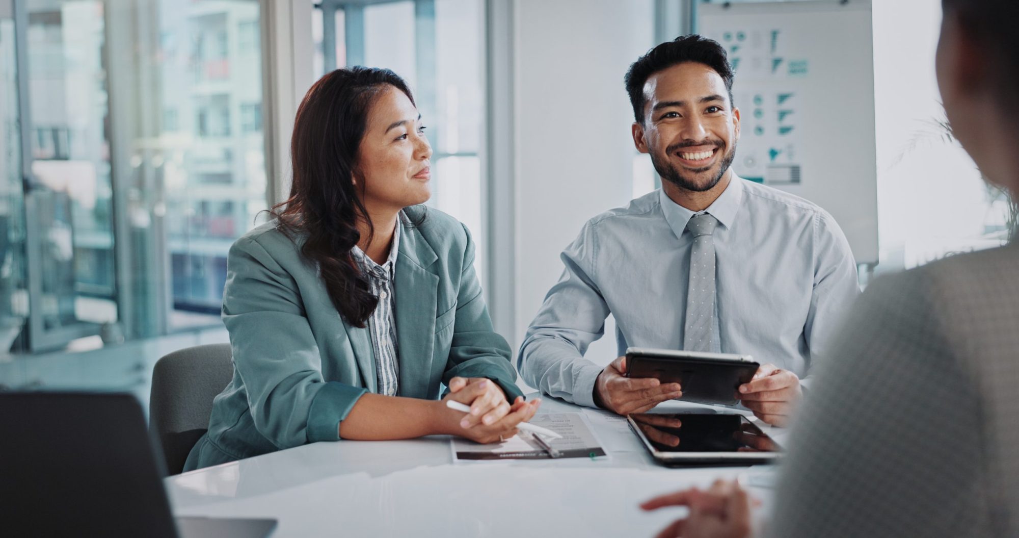 Two people in business attire sit at a table, engaging in conversation about LaGrange Estate Planning. One is holding a tablet.