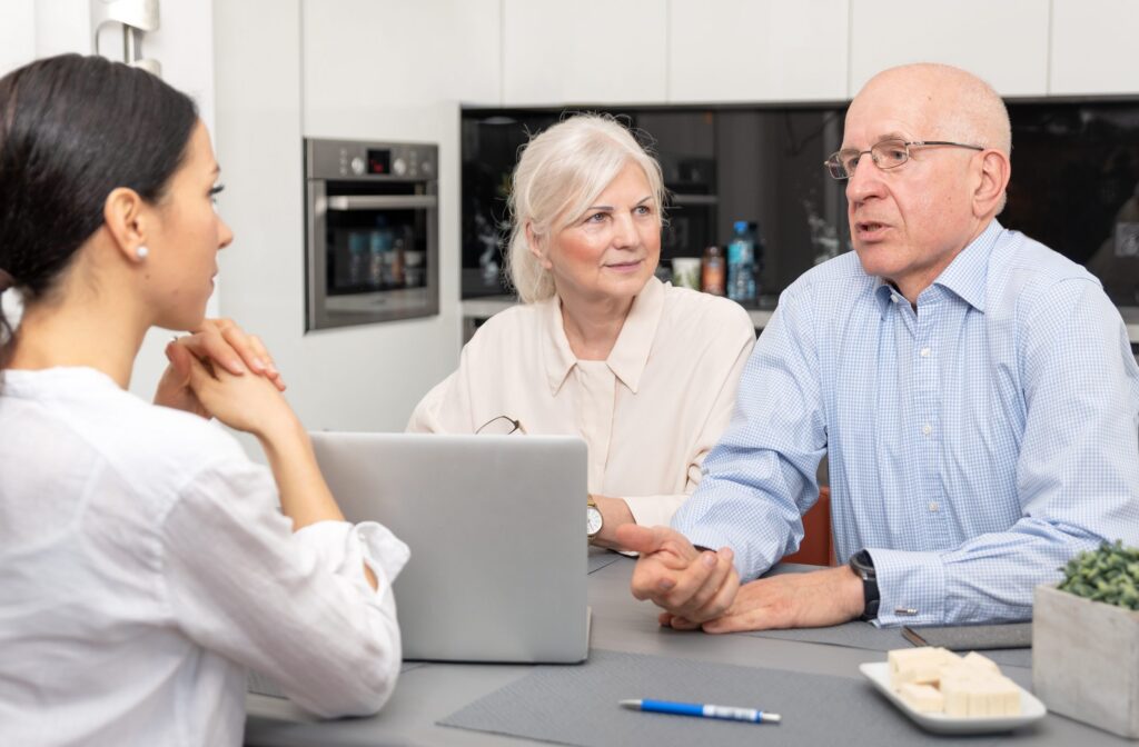 Three people sit at a table engaged in a conversation about Brookfield Elder Law. A woman types on her laptop while an older man and woman listen intently.