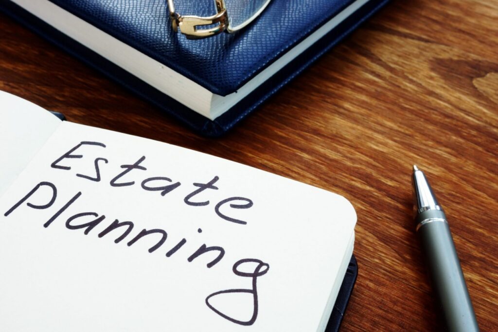 Notebook open to a page labeled "Estate Planning," placed on a wooden table next to a blue binder and a silver pen, ready to guide you through LaGrange Estate Planning essentials.