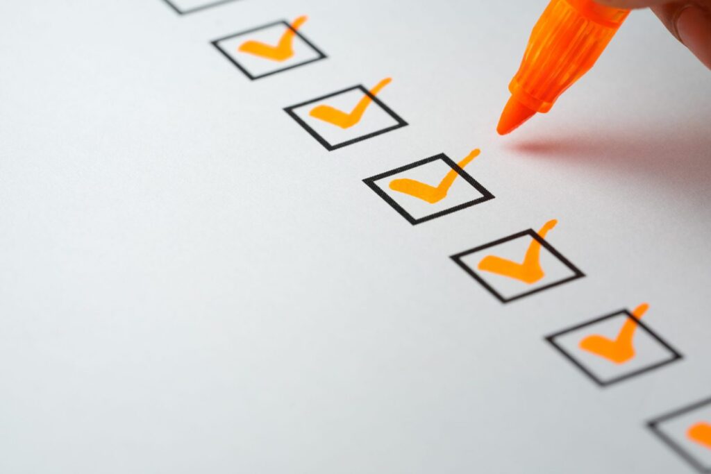 A hand holds an orange marker, marking checks in a series of boxes on a white paper, as if organizing tasks for LaGrange Estate Planning.