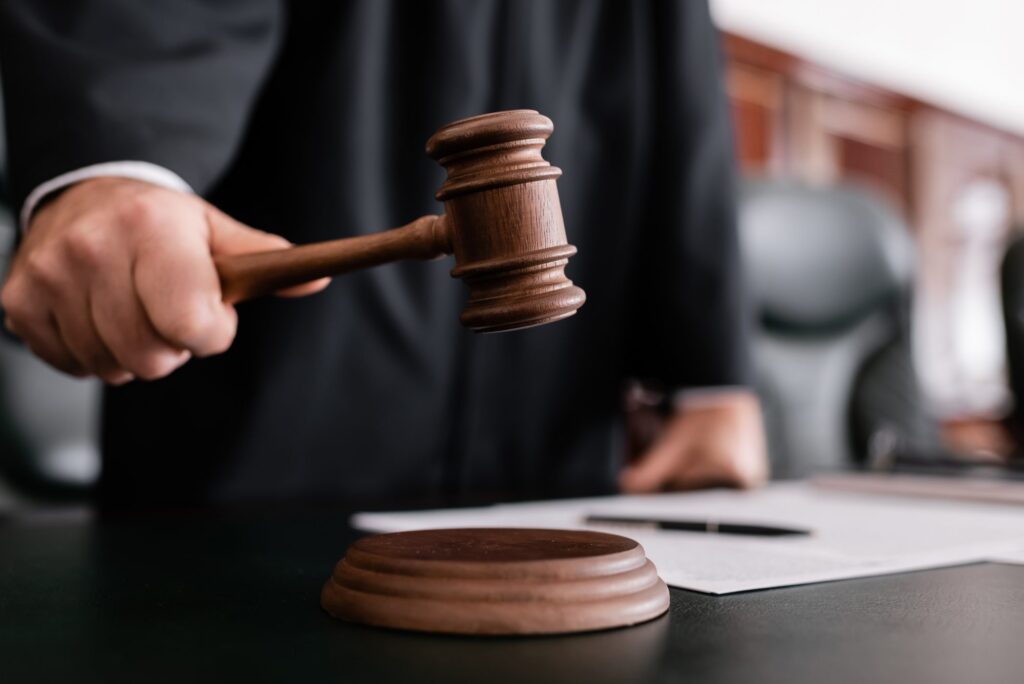 In a courtroom setting, a judge's hand holding a gavel is poised to strike a wooden sound block, possibly deliberating on matters of Brookfield Elder Law.