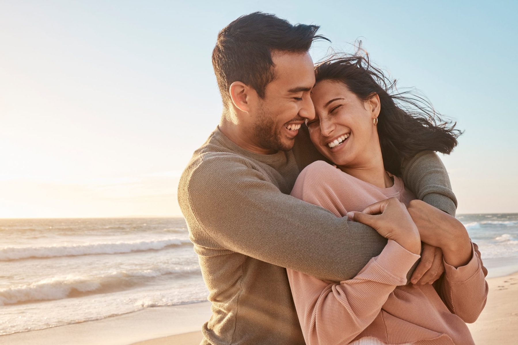 A couple embraces happily on a beach, with the ocean and a clear sky in the background, reminiscent of finding peace and assurance through LaGrange Estate Planning.